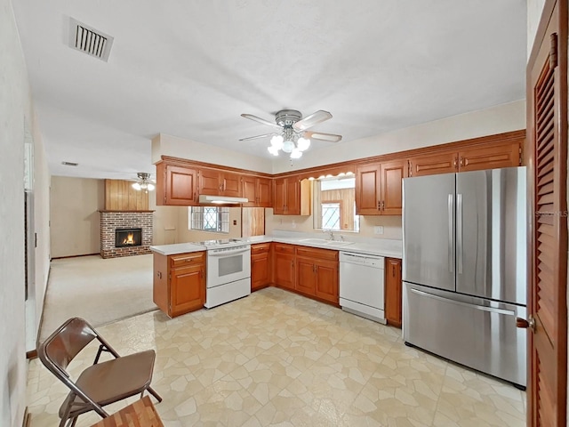 kitchen with a peninsula, white appliances, visible vents, open floor plan, and light countertops