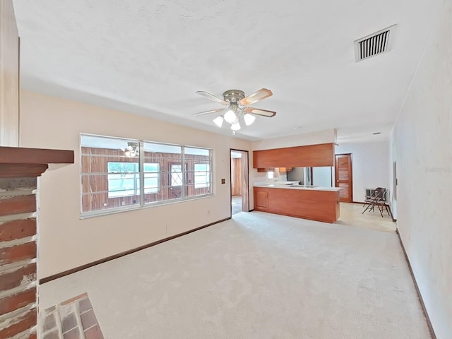 unfurnished living room featuring ceiling fan, visible vents, baseboards, and light colored carpet