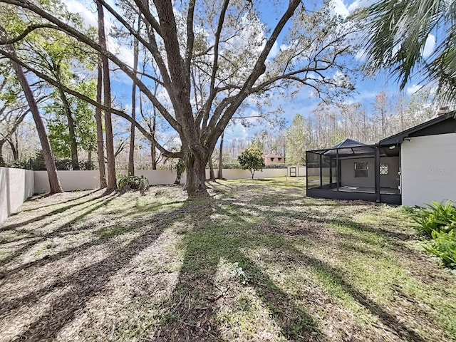 view of yard featuring glass enclosure and a fenced backyard