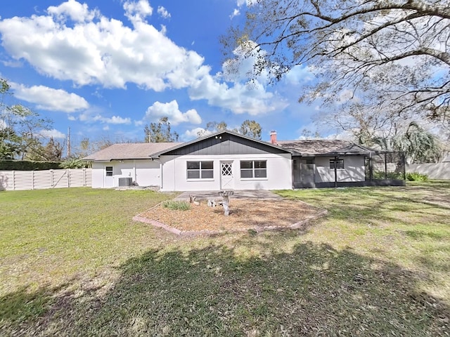 rear view of property with central AC unit, a lawn, and fence