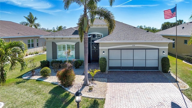 view of front of house featuring a front lawn, decorative driveway, an attached garage, and stucco siding