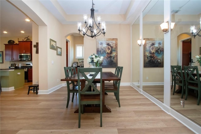 328 Siena Vista Pl, Sun City Center, FL 33573 - dining area with arched walkways, a tray ceiling, baseboards, and light wood-style floors