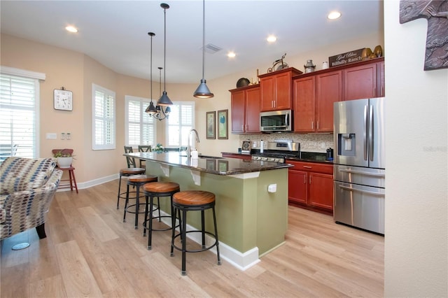 328 Siena Vista Pl, Sun City Center, FL 33573 - kitchen with light wood-style flooring, decorative backsplash, appliances with stainless steel finishes, a sink, and a kitchen breakfast bar