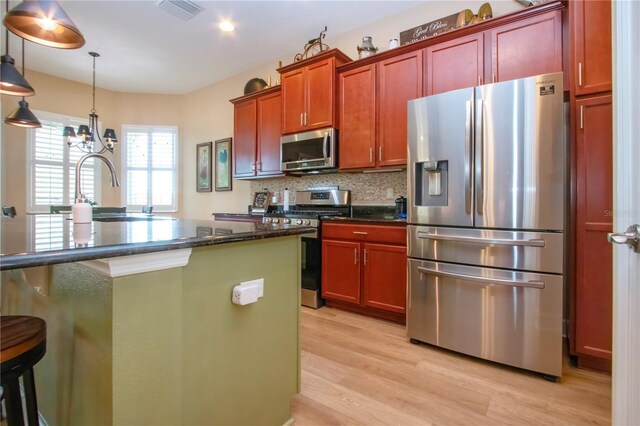328 Siena Vista Pl, Sun City Center, FL 33573 - kitchen featuring light wood finished floors, visible vents, appliances with stainless steel finishes, a sink, and backsplash