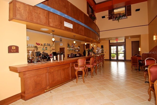 328 Siena Vista Pl, Sun City Center, FL 33573 - bar with french doors, light tile patterned floors, a high ceiling, a bar, and baseboards
