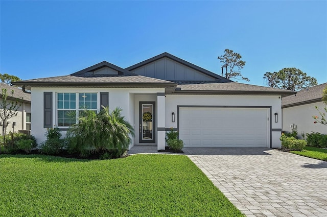 view of front of house with a garage, decorative driveway, a front lawn, board and batten siding, and stucco siding