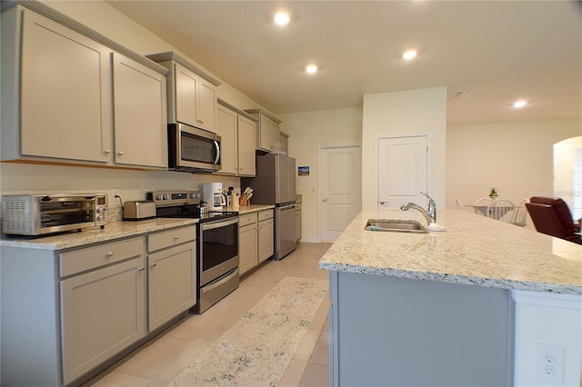 kitchen featuring a toaster, appliances with stainless steel finishes, gray cabinets, and a sink
