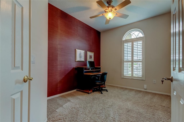 carpeted office space with a ceiling fan and baseboards