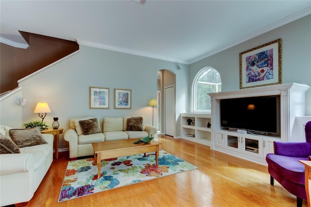 living room featuring arched walkways, ornamental molding, and wood finished floors