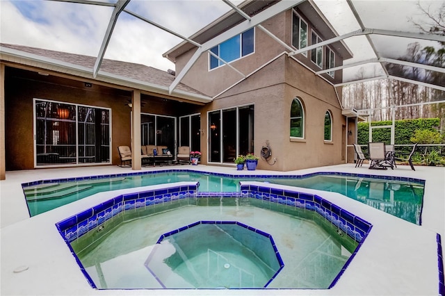 view of pool with glass enclosure, a pool with connected hot tub, and a patio area