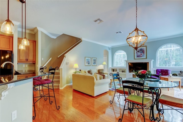 living room featuring visible vents, crown molding, light wood finished floors, and stairs