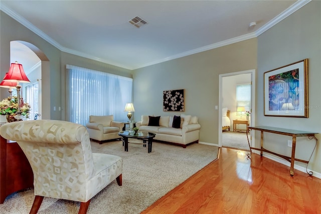 living room with light wood finished floors, baseboards, visible vents, and ornamental molding