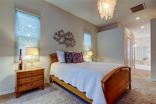 bedroom with light colored carpet, visible vents, ensuite bath, and baseboards