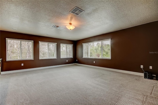 carpeted spare room featuring visible vents, a textured ceiling, and baseboards