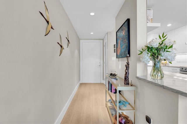 hall featuring light wood-style floors, baseboards, and recessed lighting