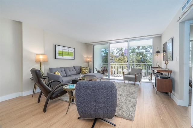 living area featuring light wood finished floors, baseboards, and a wall of windows