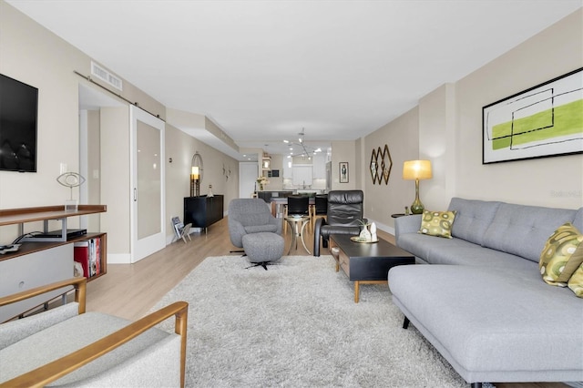 living room featuring visible vents, light wood-style flooring, and baseboards