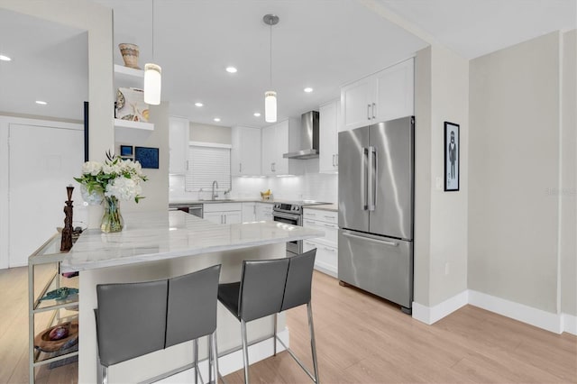 kitchen with appliances with stainless steel finishes, wall chimney range hood, a kitchen bar, and tasteful backsplash