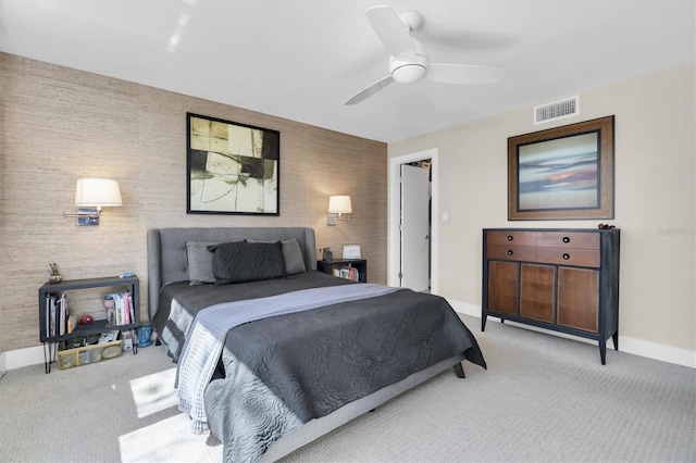 carpeted bedroom with ceiling fan, an accent wall, visible vents, and baseboards