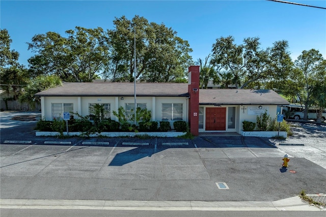 single story home with uncovered parking, a chimney, and stucco siding