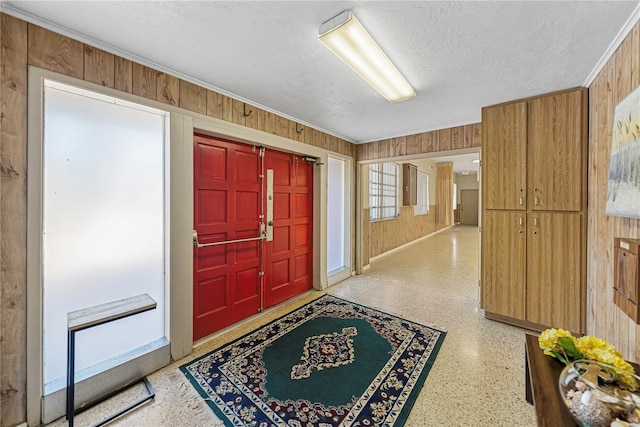 entrance foyer with wooden walls, light speckled floor, and a textured ceiling