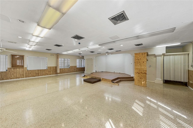 miscellaneous room with a wainscoted wall, speckled floor, and visible vents