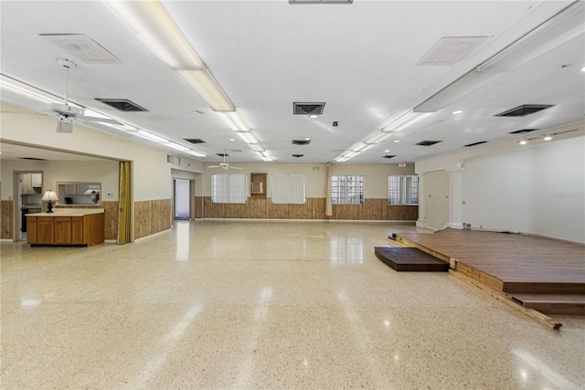 misc room with light speckled floor, visible vents, wainscoting, wood walls, and ceiling fan