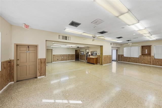 interior space with a wainscoted wall, visible vents, and wooden walls