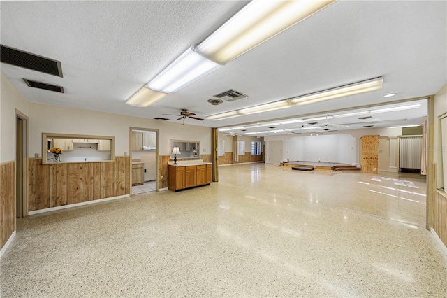 misc room with light speckled floor, visible vents, a textured ceiling, and wooden walls