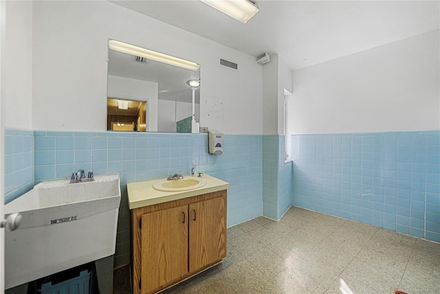 bathroom with tile walls, wainscoting, visible vents, and vanity