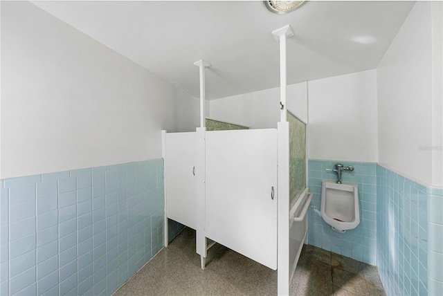 full bathroom featuring wainscoting and tile walls