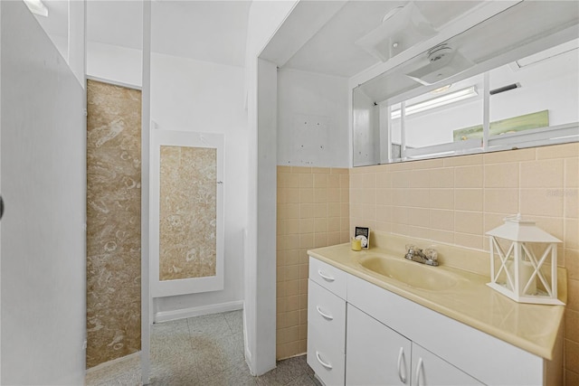 bathroom with a wainscoted wall, tile walls, and vanity