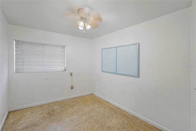 spare room featuring a ceiling fan and baseboards