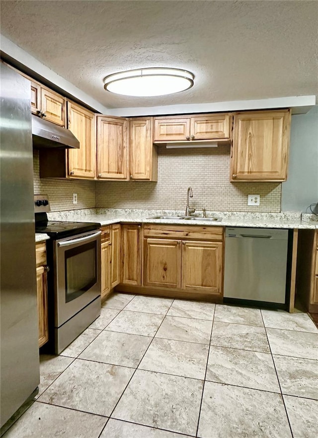 kitchen with decorative backsplash, stainless steel appliances, light countertops, under cabinet range hood, and a sink