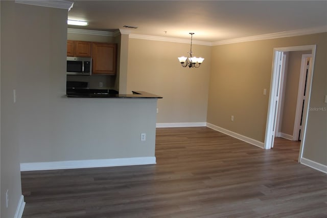 kitchen featuring visible vents, hanging light fixtures, ornamental molding, stainless steel microwave, and dark countertops