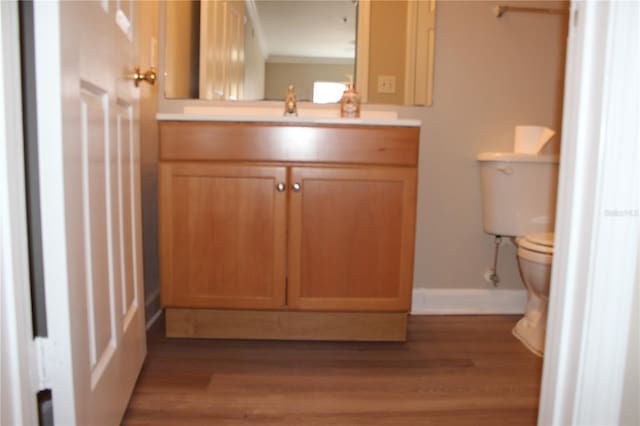 bathroom featuring toilet, wood finished floors, vanity, and baseboards