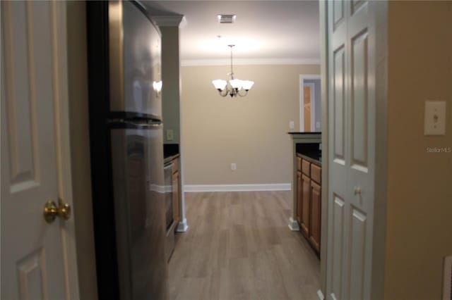 corridor with light wood-style floors, a chandelier, crown molding, and baseboards