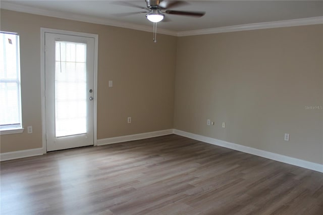 spare room featuring light wood-style floors, plenty of natural light, baseboards, and crown molding