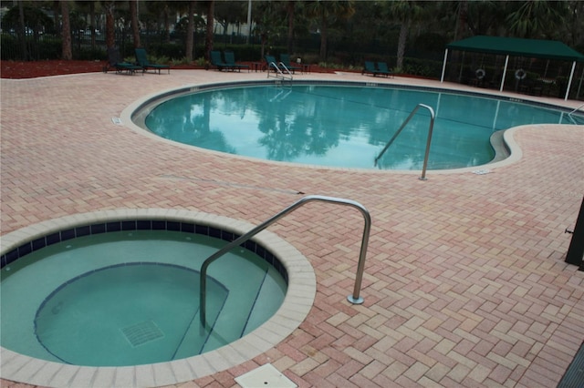 pool with a patio area and a community hot tub