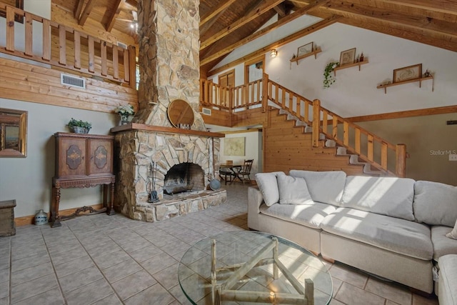 tiled living area featuring beam ceiling, stairway, a fireplace, and high vaulted ceiling