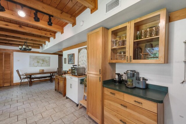 kitchen featuring visible vents, beam ceiling, dark countertops, wooden ceiling, and glass insert cabinets