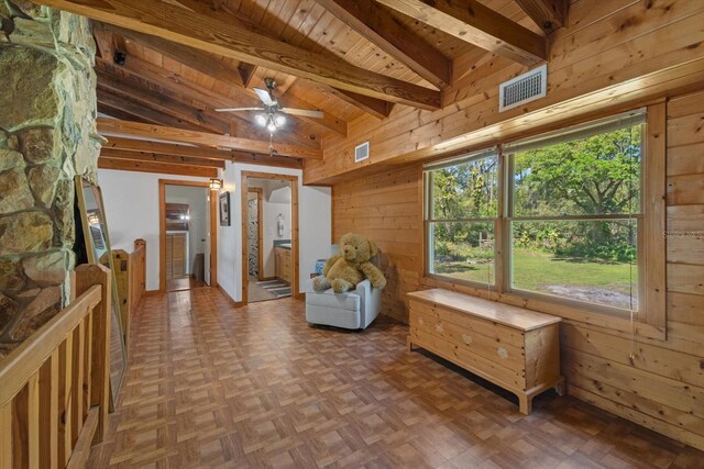 sitting room featuring visible vents, wood walls, wooden ceiling, and lofted ceiling with beams