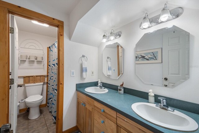 bathroom with a sink, toilet, double vanity, and tile patterned flooring