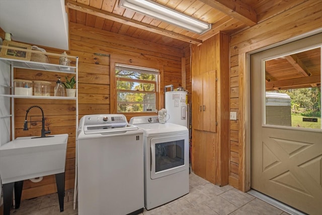 washroom with wooden walls, electric water heater, washing machine and dryer, wood ceiling, and laundry area