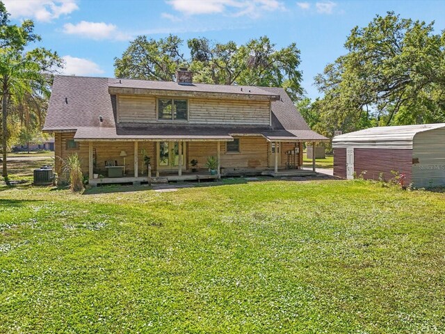 back of property with covered porch, central AC, a chimney, an outdoor structure, and a lawn