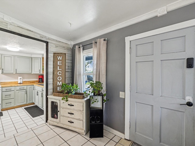 foyer entrance featuring light tile patterned floors, baseboards, and ornamental molding