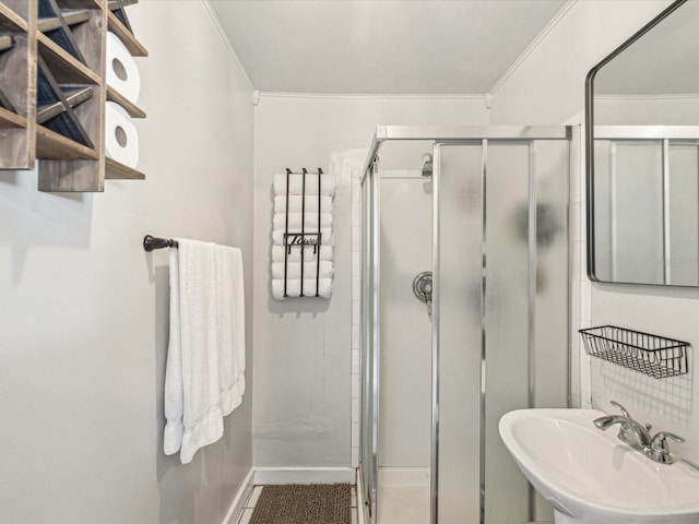 full bath featuring baseboards, ornamental molding, a sink, and a shower stall