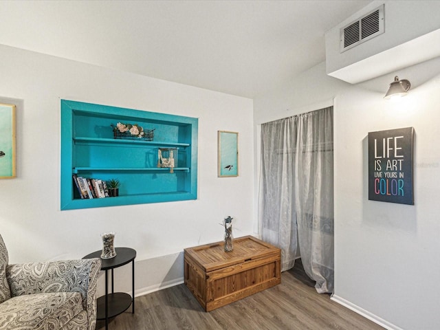 living area with visible vents, baseboards, and wood finished floors