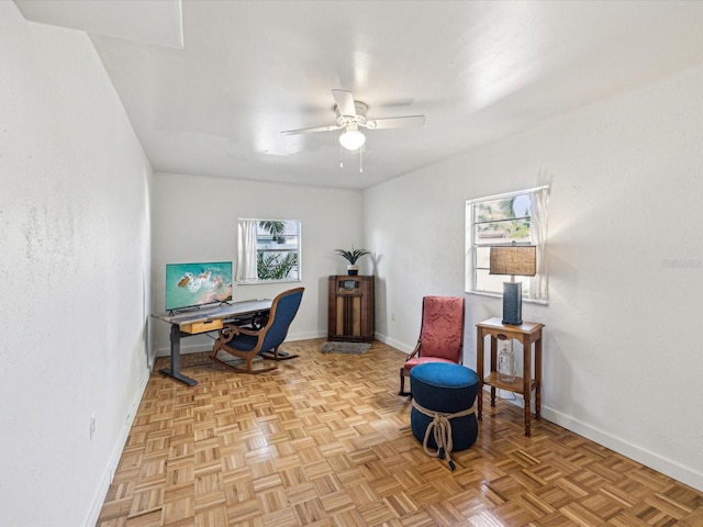 office area with ceiling fan and baseboards