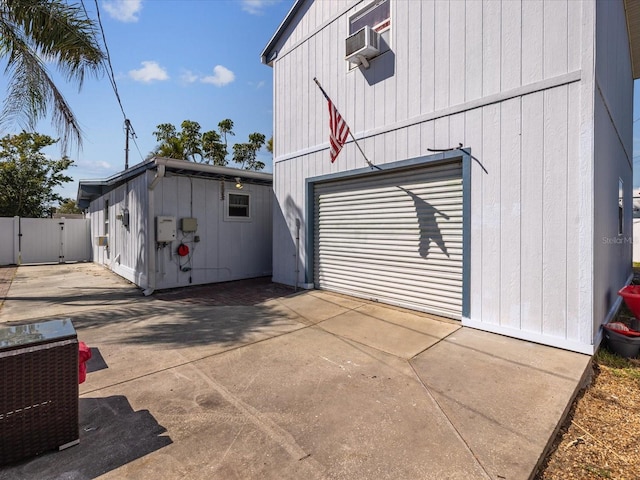 view of property exterior with central air condition unit, a garage, fence, concrete driveway, and a gate